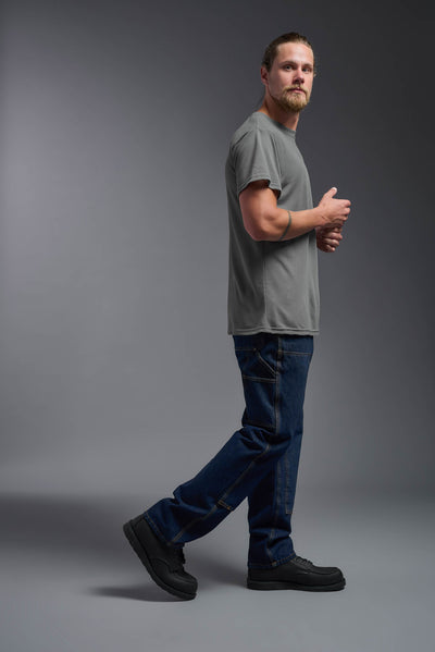 A male caucasian model with a beard wearing the men's DuroSoft Outdoor Tee in the color army gray on a gray background, made out of 100% filament polyester that feels like soft cotton, showing the modern fit from a side view. This shirt is anti-snagging, quick-drying and moisture-wicking and is made in the USA. #color_army-gray