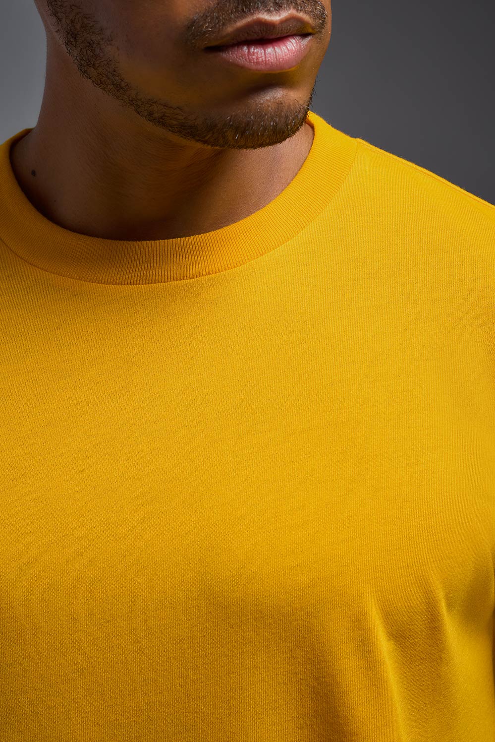 A male African American model with a beard wearing the men's DuroSoft Outdoor Tee in the color army yellow on a gray background, made out of 100% filament polyester that feels like soft cotton, showing the modern fit from a closeup collar detail view. This shirt is anti-snagging, quick-drying and moisture-wicking and is made in the USA. #color_army-yellow