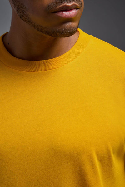 A male African American model with a beard wearing the men's DuroSoft Outdoor Tee in the color army yellow on a gray background, made out of 100% filament polyester that feels like soft cotton, showing the modern fit from a closeup collar detail view. This shirt is anti-snagging, quick-drying and moisture-wicking and is made in the USA. #color_army-yellow