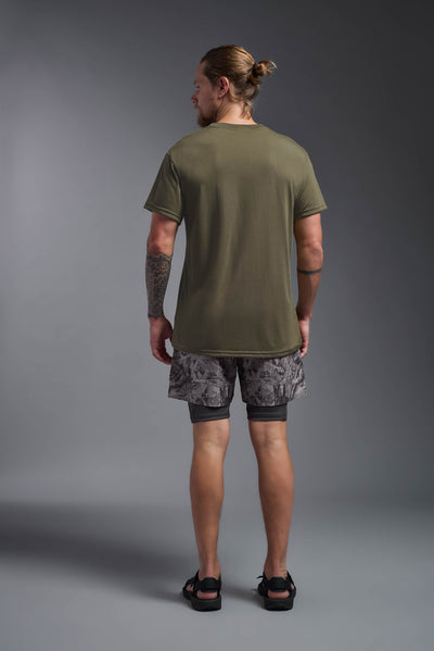 A male caucasian model with a beard wearing the men's DuroSoft Outdoor Tee in the color tan 499 on a gray background, made out of 100% filament polyester that feels like soft cotton, showing the modern fit from a back view. This shirt is anti-snagging, quick-drying and moisture-wicking and is made in the USA. #color_tan-499