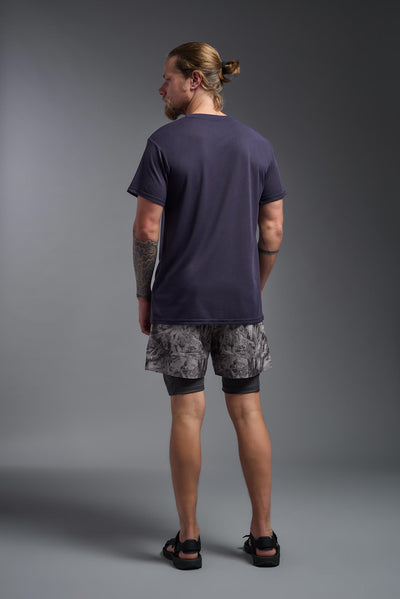 A male caucasian model with a beard wearing the men's DuroSoft Outdoor Tee in the color army blue on a gray background, made out of 100% filament polyester that feels like soft cotton, showing the modern fit from a back view. This shirt is anti-snagging, quick-drying and moisture-wicking and is made in the USA. #color_army-blue