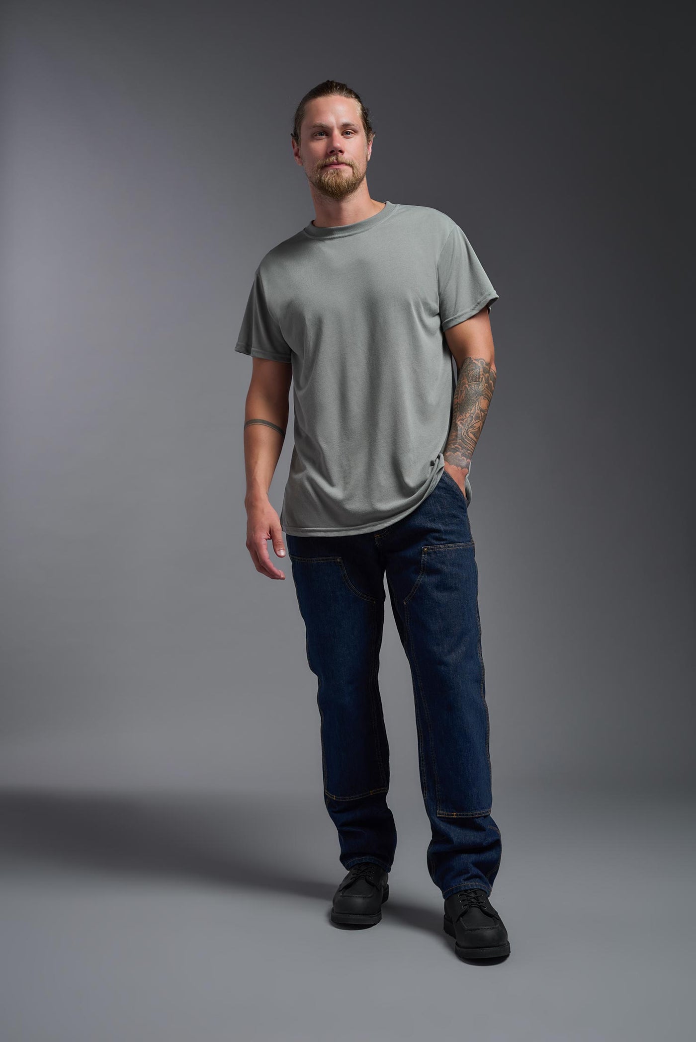 A male caucasian model with a beard wearing the men's DuroSoft Outdoor Tee in the color army gray on a gray background, made out of 100% filament polyester that feels like soft cotton, showing the modern fit from a front view. This shirt is anti-snagging, quick-drying and moisture-wicking and is made in the USA. #color_army-gray