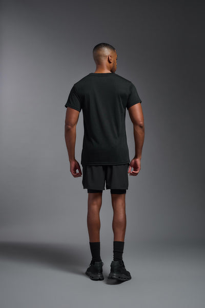 A male African American model with a beard wearing the men's DuroSoft Outdoor Tee in the color black on a gray background, made out of 100% filament polyester that feels like soft cotton, showing the modern fit from a back view. This shirt is anti-snagging, quick-drying and moisture-wicking and is made in the USA. #color_black