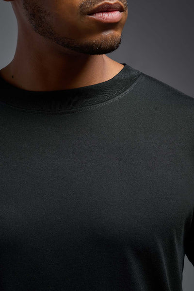 A male African American model with a beard wearing the men's DuroSoft Outdoor Tee in the color black on a gray background, made out of 100% filament polyester that feels like soft cotton, showing the modern fit from a front view. This shirt is anti-snagging, quick-drying and moisture-wicking and is made in the USA. #color_black