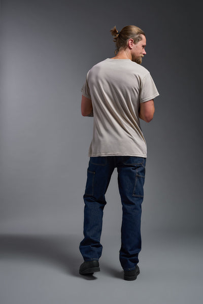 A male caucasian model with a beard wearing the men's DuroSoft Outdoor Tee in the color desert on a gray background, made out of 100% filament polyester that feels like soft cotton, showing the modern fit from a back view. This shirt is anti-snagging, quick-drying and moisture-wicking and is made in the USA. #color_desert