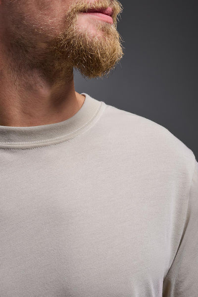 A male caucasian model with a beard wearing the men's DuroSoft Outdoor Tee in the color desert on a gray background, made out of 100% filament polyester that feels like soft cotton, showing the modern fit from a collar close-up view. This shirt is anti-snagging, quick-drying and moisture-wicking and is made in the USA. #color_desert