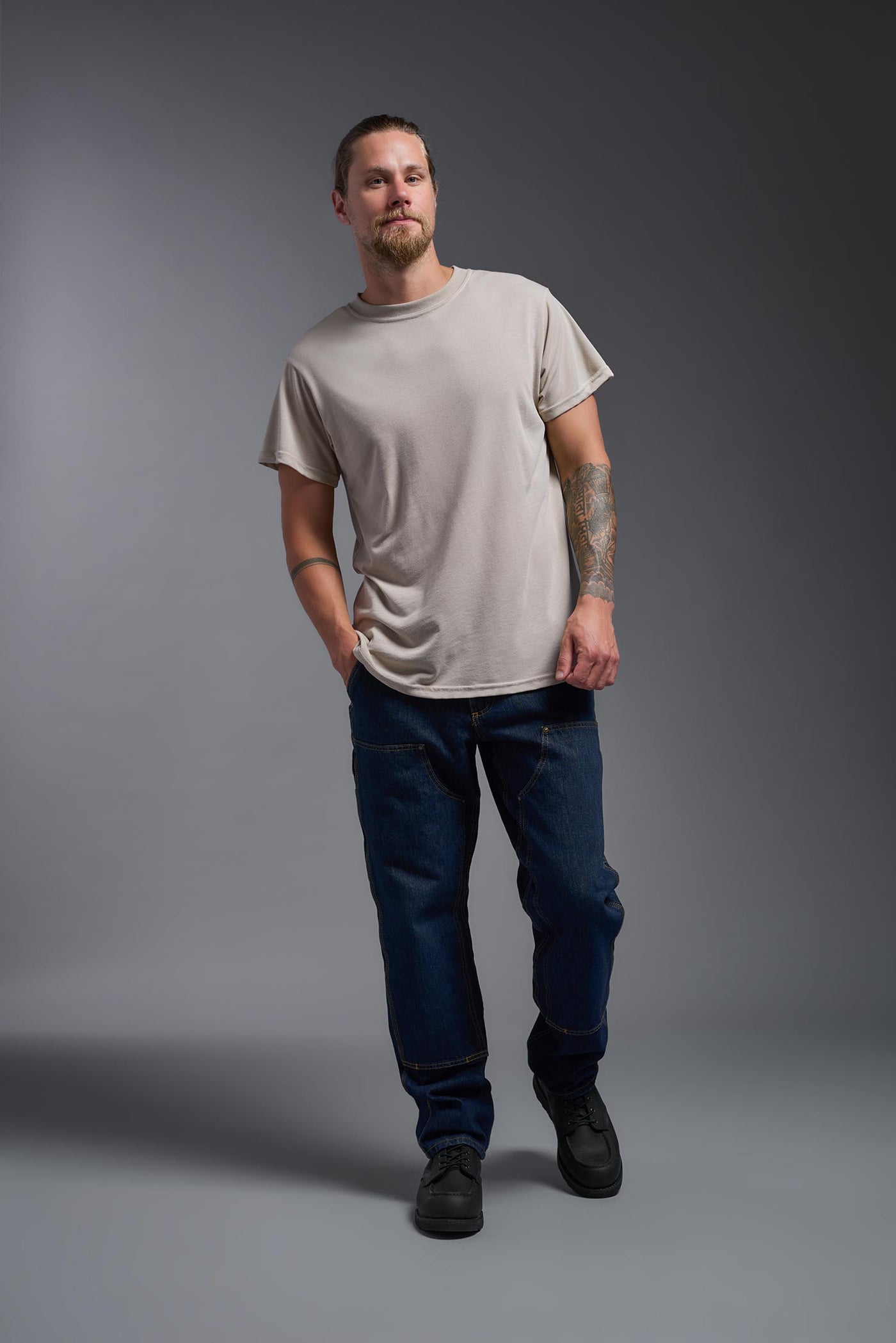 A male caucasian model with a beard wearing the men's DuroSoft Outdoor Tee in the color desert on a gray background, made out of 100% filament polyester that feels like soft cotton, showing the modern fit from a front view. This shirt is anti-snagging, quick-drying and moisture-wicking and is made in the USA. #color_desert