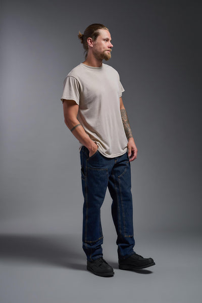 A male caucasian model with a beard wearing the men's DuroSoft Outdoor Tee in the color desert on a gray background, made out of 100% filament polyester that feels like soft cotton, showing the modern fit from a side view. This shirt is anti-snagging, quick-drying and moisture-wicking and is made in the USA. #color_desert