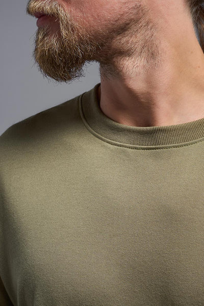 A male caucasian model with a beard wearing the men's DuroSoft Outdoor Tee in the color tan 499 on a gray background, made out of 100% filament polyester that feels like soft cotton, showing the modern fit from a close-up collar view. This shirt is anti-snagging, quick-drying and moisture-wicking and is made in the USA. #color_tan-499