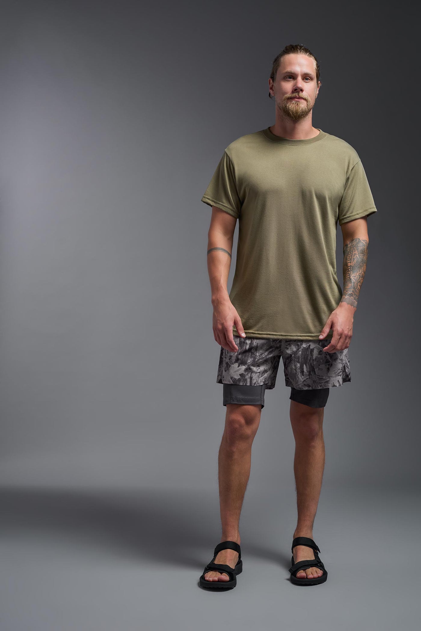 A male caucasian model with a beard wearing the men's DuroSoft Outdoor Tee in the color tan 499 on a gray background, made out of 100% filament polyester that feels like soft cotton, showing the modern fit from a front view. This shirt is anti-snagging, quick-drying and moisture-wicking and is made in the USA. #color_tan-499