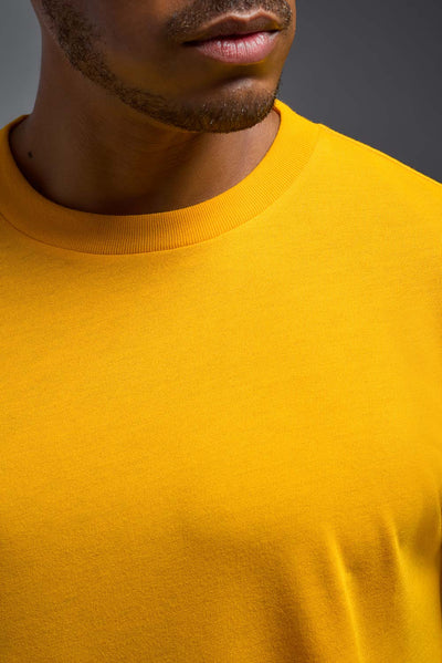 A male model wearing the men's DuroSoft Outdoor Tee in the color yellow on a gray background, made out of 100% filament polyester that feels like soft cotton, showing the modern fit from a collar close-up view. This shirt is anti-snagging, quick-drying and moisture-wicking and is made in the USA. #color_yellow