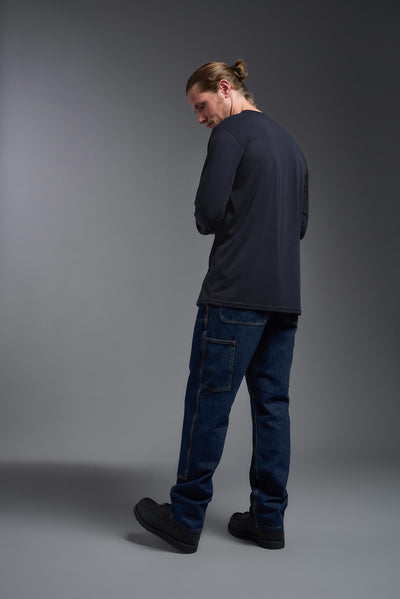 A male Caucasian model with a blonde hair and a beard wearing the men's DuroSoft Outdoor Long Sleeve in the color army blue on a gray background, made out of 100% filament polyester that feels like soft cotton, showing the modern fit from a back view. This shirt is anti-snagging, quick-drying and moisture-wicking and is made in the USA. #color_army-blue