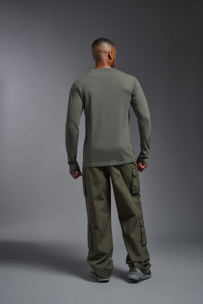 A male Caucasian model with a blonde hair and a beard wearing the men's DuroSoft Outdoor Long Sleeve in the color army gray on a gray background, made out of 100% filament polyester that feels like soft cotton, showing the modern fit from a back view. This shirt is anti-snagging, quick-drying and moisture-wicking and is made in the USA. #color_army-gray