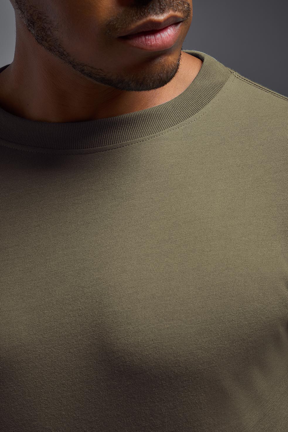 A male African American model with a beard wearing the men's DuroSoft Outdoor Long Sleeve in the color tan 499 on a gray background, made out of 100% filament polyester that feels like soft cotton, showing the modern fit from a closeup collar front view. This shirt is anti-snagging, quick-drying and moisture-wicking and is made in the USA. #color_tan-499