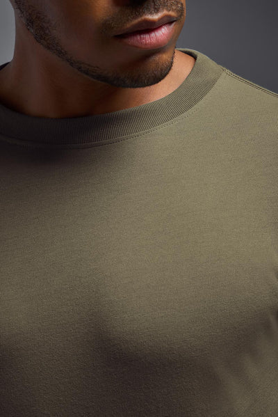 A male African American model with a beard wearing the men's DuroSoft Outdoor Long Sleeve in the color tan 499 on a gray background, made out of 100% filament polyester that feels like soft cotton, showing the modern fit from a closeup collar front view. This shirt is anti-snagging, quick-drying and moisture-wicking and is made in the USA. #color_tan-499