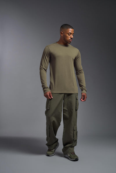 A male African American model with a beard wearing the men's DuroSoft Outdoor Long Sleeve in the color tan 499 on a gray background, made out of 100% filament polyester that feels like soft cotton, showing the modern fit from a front view. This shirt is anti-snagging, quick-drying and moisture-wicking and is made in the USA. #color_tan-499
