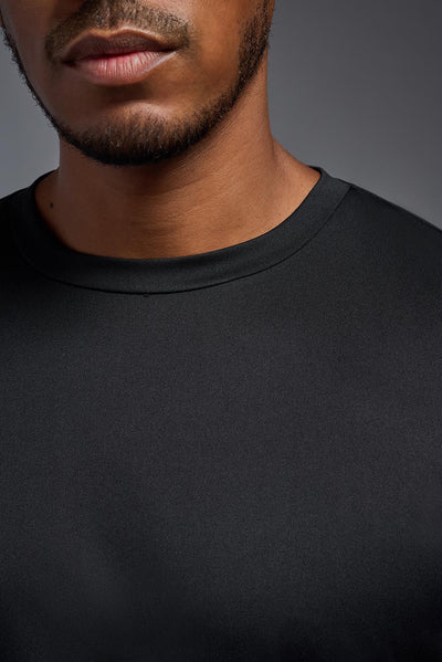 A male African American model with a beard wearing the men's EcoTek™ Recycled Performance Tee in the color black, made out of 100% recycled polyester REPREVE®, showing the modern fit from a collar close-up view. This shirt features a mechanical stretch, quick-dries, wicks moisture and is made in the USA. #color_black