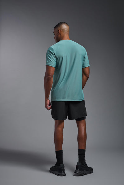 A male African American model with a beard wearing the men's EcoTek™ Recycled Performance Tee in the color juniper, made out of 100% recycled polyester REPREVE®, showing the modern fit from a back view. This shirt features a mechanical stretch, quick-dries, wicks moisture and is made in the USA. #color_juniper