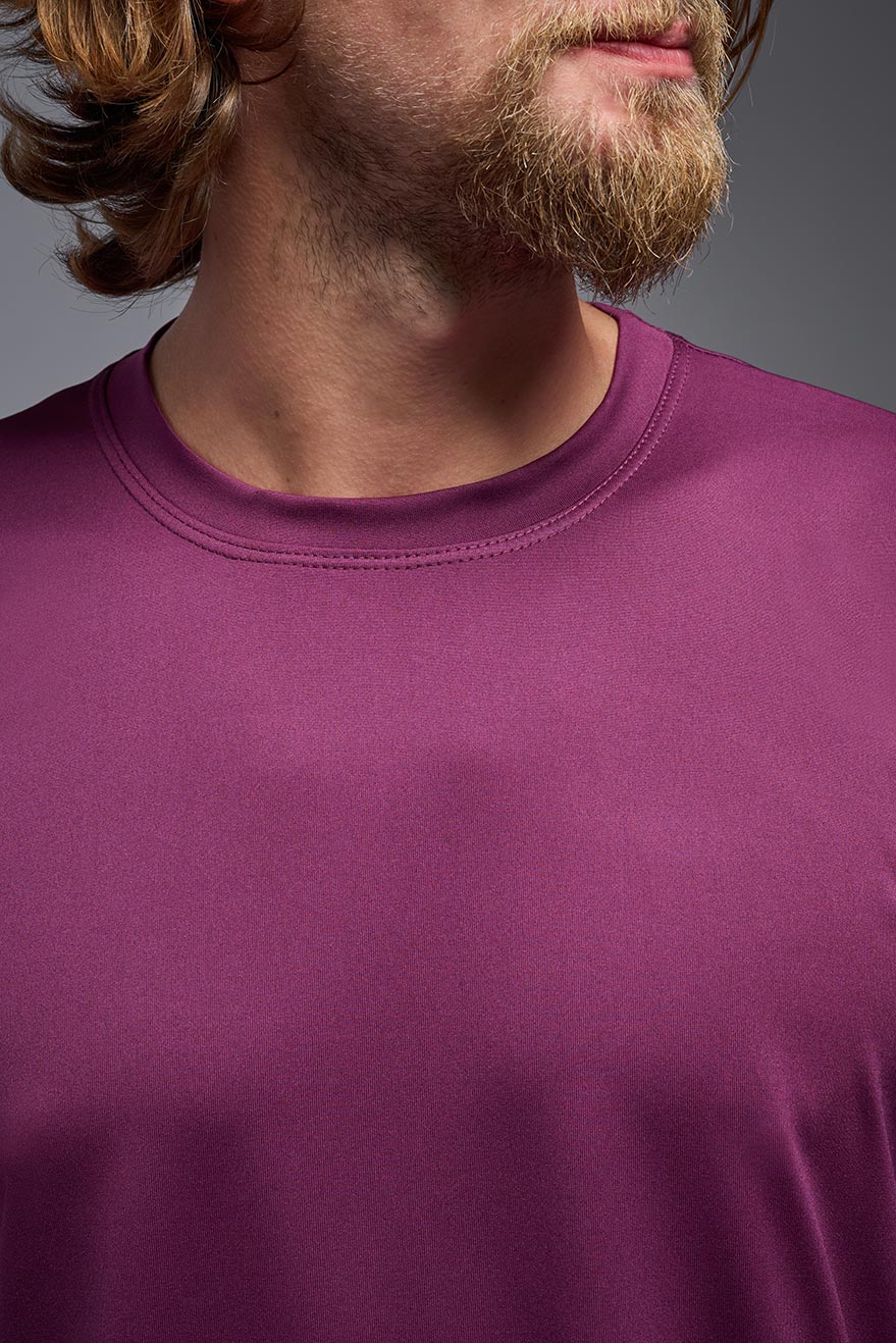 A blonde, male model with a beard wearing the men's EcoTek™ Recycled Performance Tee in the color merlot, made out of 100% recycled polyester REPREVE®, showing the modern fit from a front view. This shirt features a mechanical stretch, quick-dries, wicks moisture and is made in the USA. #color_merlot
