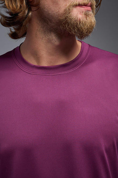 A blonde, male model with a beard wearing the men's EcoTek™ Recycled Performance Tee in the color merlot, made out of 100% recycled polyester REPREVE®, showing the modern fit from a front view. This shirt features a mechanical stretch, quick-dries, wicks moisture and is made in the USA. #color_merlot