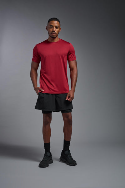 An African American, male model with a beard wearing the men's EcoTek™ Recycled Performance Tee in the color poinsettia, made out of 100% recycled polyester REPREVE®, showing the modern fit from a front view. This shirt features a mechanical stretch, quick-dries, wicks moisture and is made in the USA. #color_poinsettia