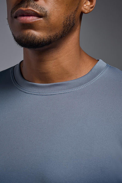 An African American, male model with a beard wearing the men's EcoTek™ Recycled Performance Tee in the color tahoe blue, made out of 100% recycled polyester REPREVE®, showing the modern fit from a close-up collar view. This shirt features a mechanical stretch, quick-dries, wicks moisture and is made in the USA. #color_tahoe
