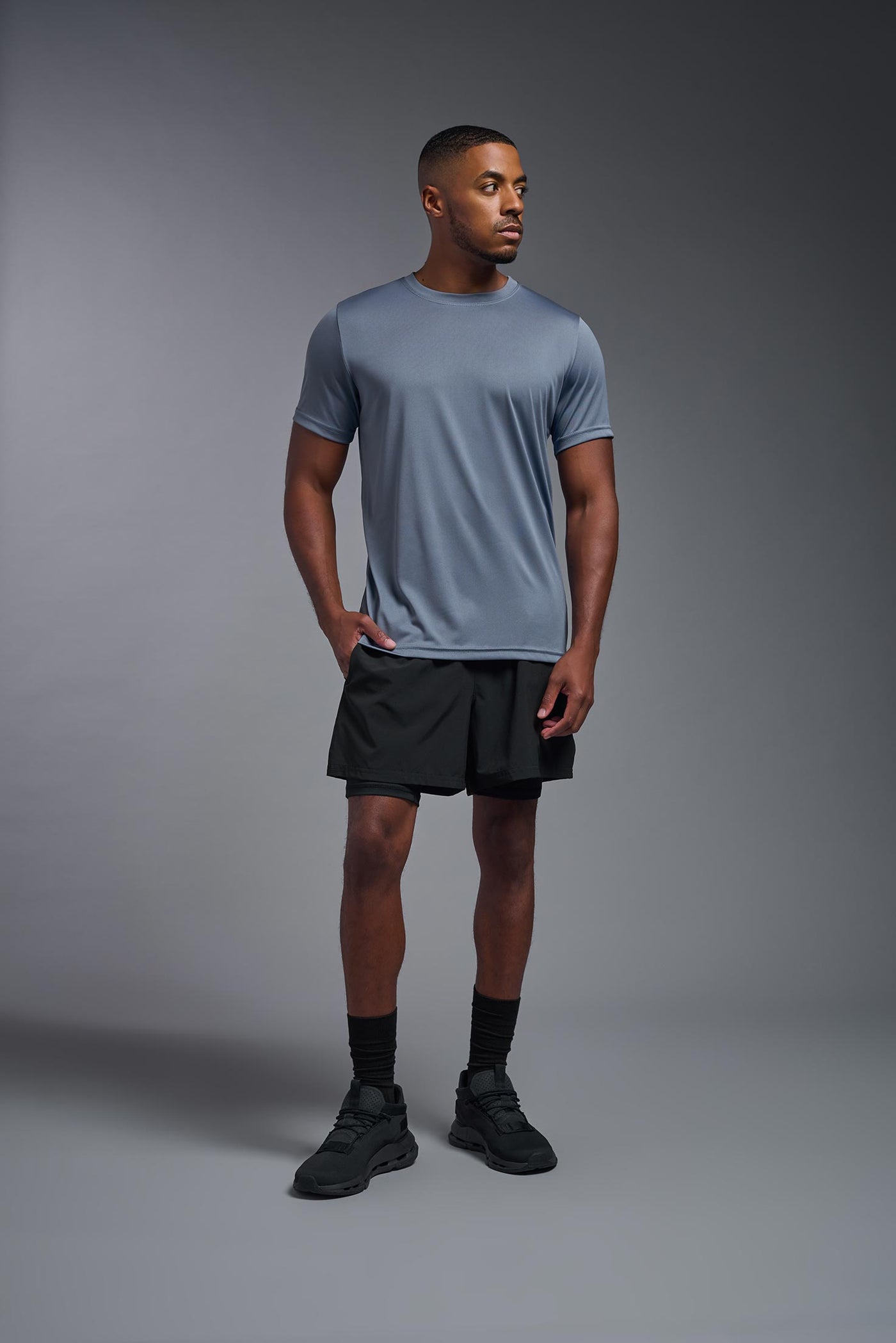 An African American, male model with a beard wearing the men's EcoTek™ Recycled Performance Tee in the color tahoe blue, made out of 100% recycled polyester REPREVE®, showing the modern fit from a front view. This shirt features a mechanical stretch, quick-dries, wicks moisture and is made in the USA. #color_tahoe