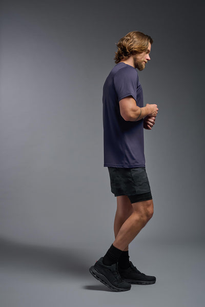 A blonde, male model with a beard wearing the men's EcoTek™ Recycled Performance Tee in the color twilight, made out of 100% recycled polyester REPREVE®, showing the modern fit from a side view. This shirt features a mechanical stretch, quick-dries, wicks moisture and is made in the USA. #color_twilight