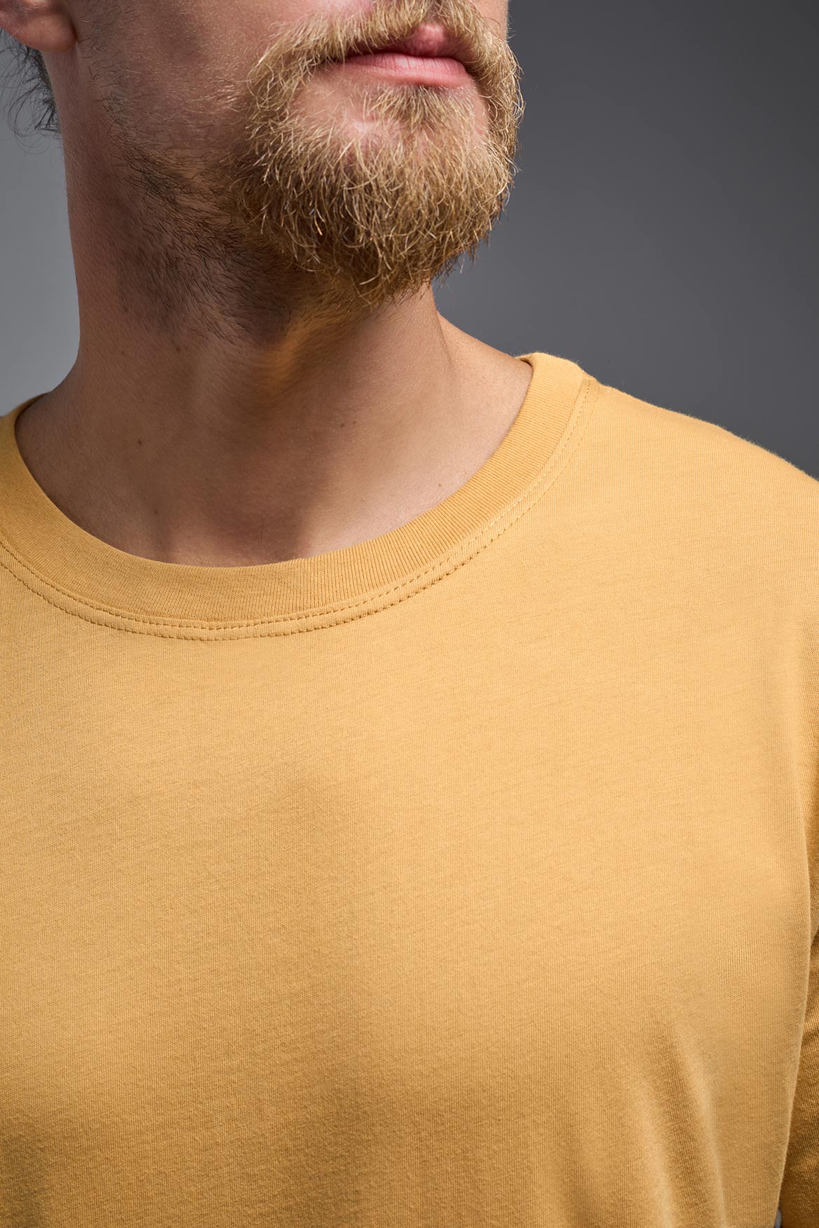 A male model wearing the unisex Organic Soft Cotton T-shirt in the color harvest, made from 100% certified organic cotton, shot from a closeup colla front view. This shirt is unisex and made in the USA. #color_harvest