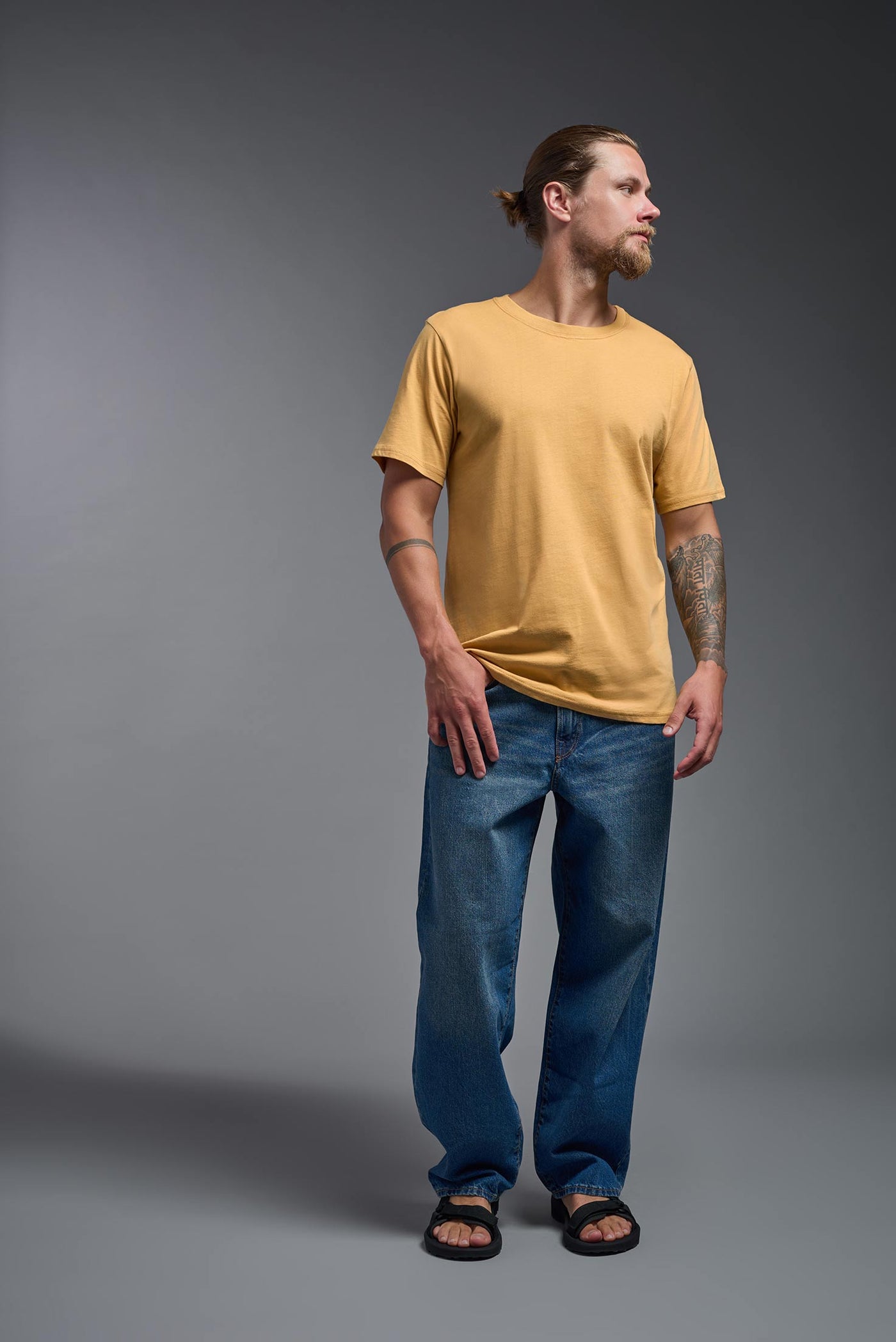 A male model wearing the unisex Organic Soft Cotton T-shirt in the color harvest, made from 100% certified organic cotton, shot from a full body front view. This shirt is unisex and made in the USA. #color_harvest