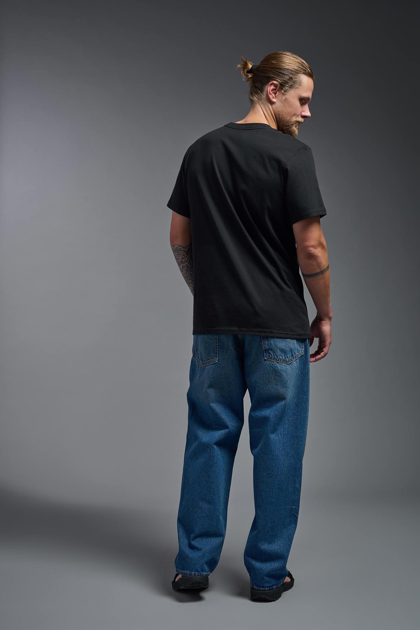 A male and female model wearing the unisex Organic Soft Cotton T-shirt in the color black, made from 100% certified organic cotton, shot from a full body back view. This shirt is unisex and made in the USA. #color_black