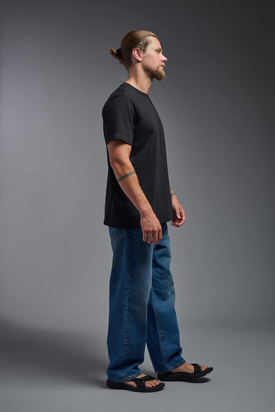 A male and female model wearing the unisex Organic Soft Cotton T-shirt in the color black, made from 100% certified organic cotton, shot from a full body side view. This shirt is unisex and made in the USA. #color_black