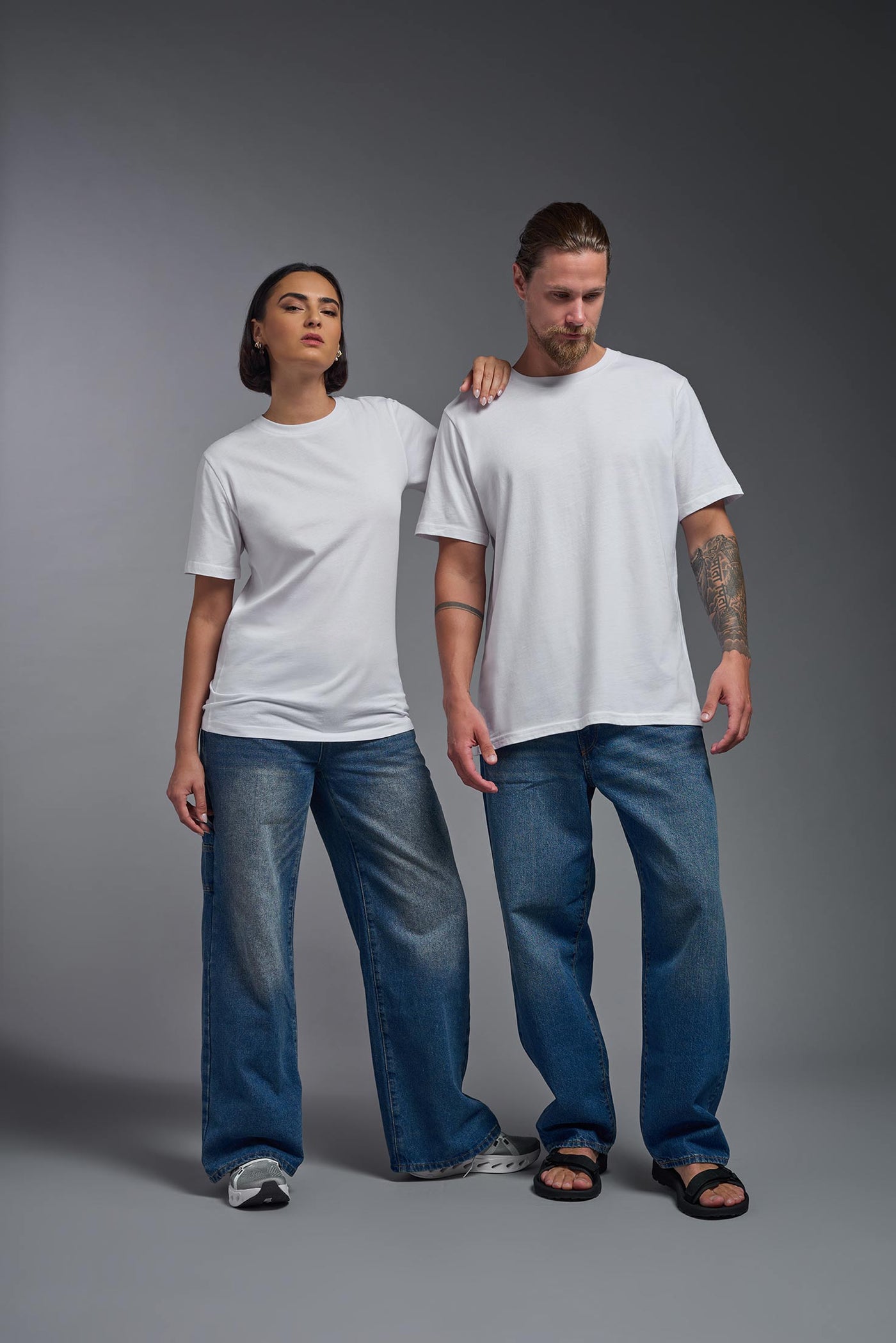 A male and female model wearing the unisex Organic Soft Cotton T-shirt in the color white, made from 100% certified organic cotton, shot from a full body front view. This shirt is unisex and made in the USA. #color_white
