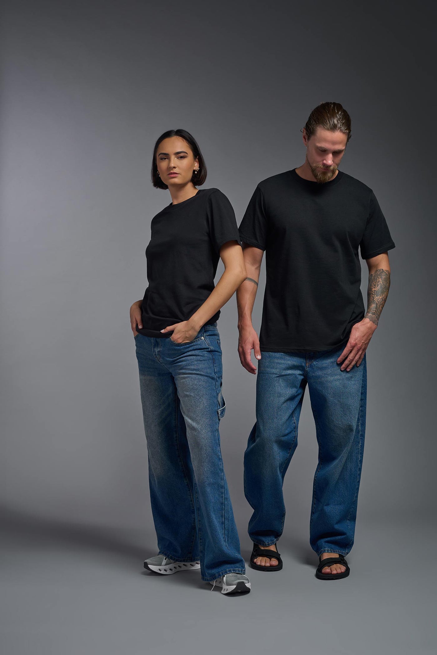 A male and female model wearing the unisex Organic Soft Cotton T-shirt in the color black, made from 100% certified organic cotton, shot from a full body front view. This shirt is unisex and made in the USA. #color_black