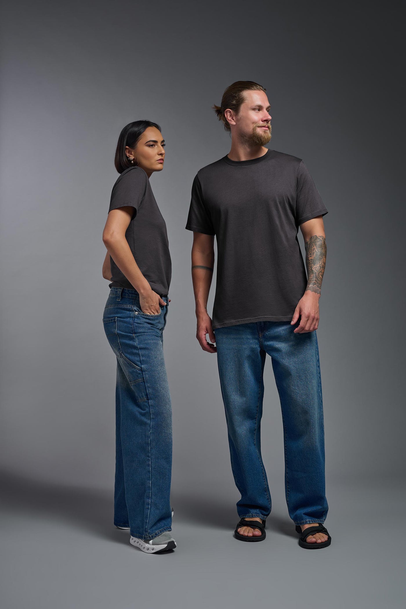 A male and female model wearing the unisex Organic Soft Cotton T-shirt in the color nova, made from 100% certified organic cotton, shot from a full body front view. This shirt is unisex and made in the USA. #color_carbon
