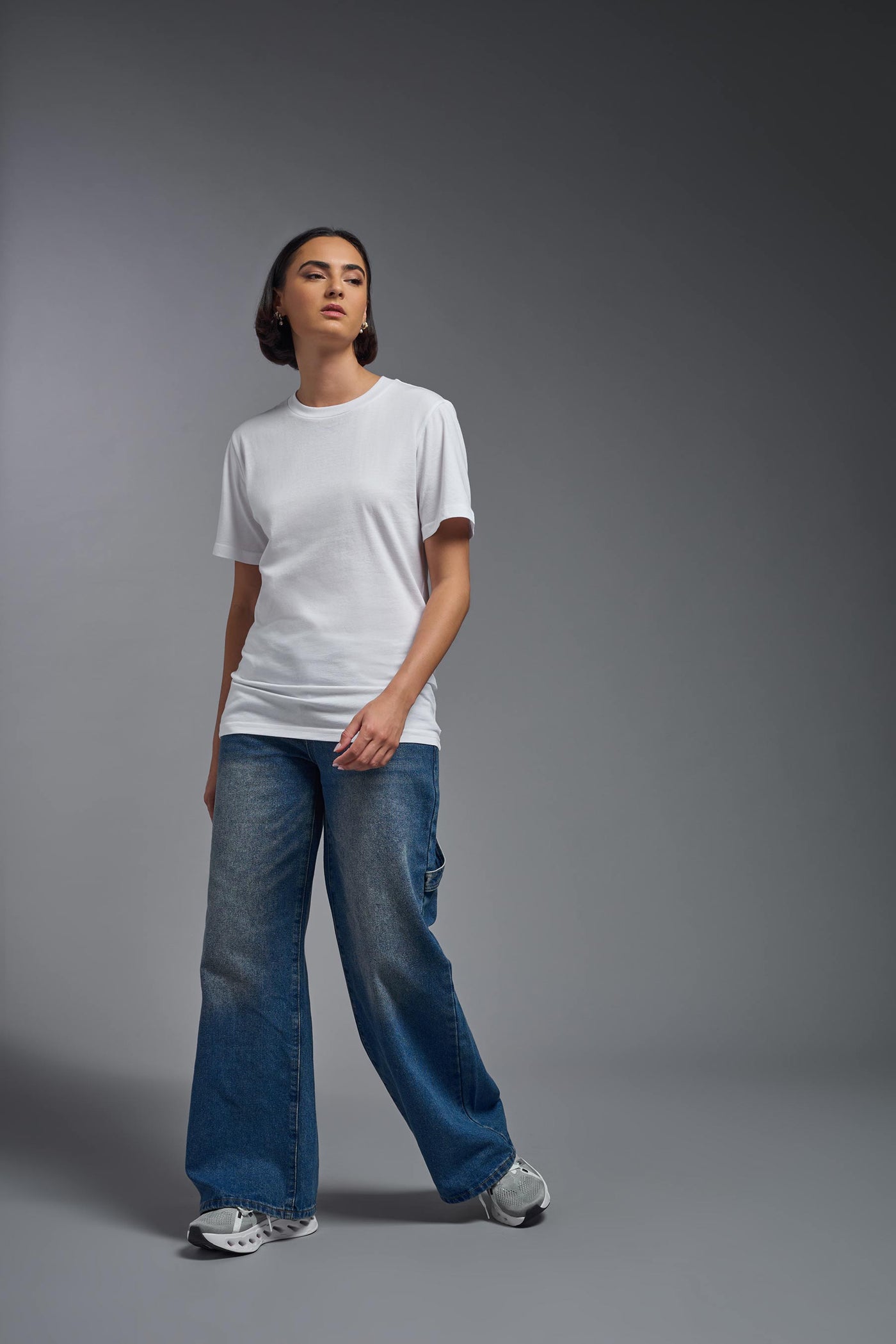 A female model wearing the unisex Organic Soft Cotton T-shirt in the color white, made from 100% certified organic cotton, shot from a full body front view. This shirt is unisex and made in the USA. #color_white