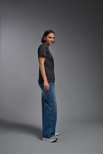 A female model wearing the unisex Organic Soft Cotton T-shirt in the color nova, made from 100% certified organic cotton, shot from a full body side view. This shirt is unisex and made in the USA. #color_carbon