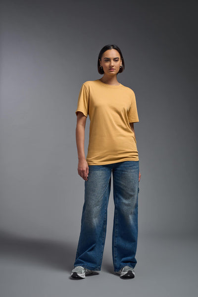 A female model wearing the unisex Organic Soft Cotton T-shirt in the color harvest, made from 100% certified organic cotton, shot from a full body front view. This shirt is unisex and made in the USA. #color_harvest