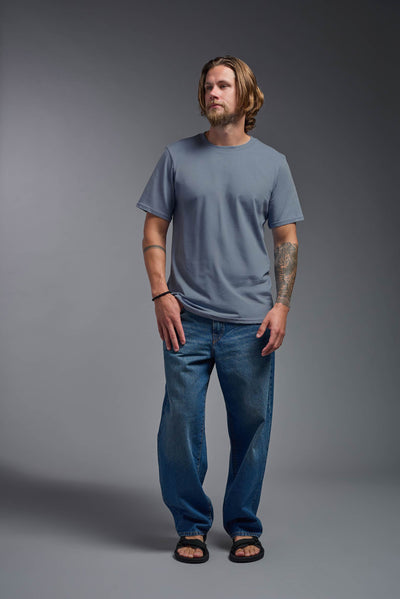 A male model wearing the unisex Organic Soft Cotton T-shirt in the color canyon blue, made from 100% certified organic cotton, shot from a full body front view. This shirt is unisex and made in the USA. #color_canyon-blue