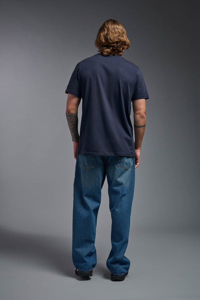 A male model wearing the unisex Organic Soft Cotton T-shirt in the color nova, made from 100% certified organic cotton, shot from a full body back view. This shirt is unisex and made in the USA. #color_nova