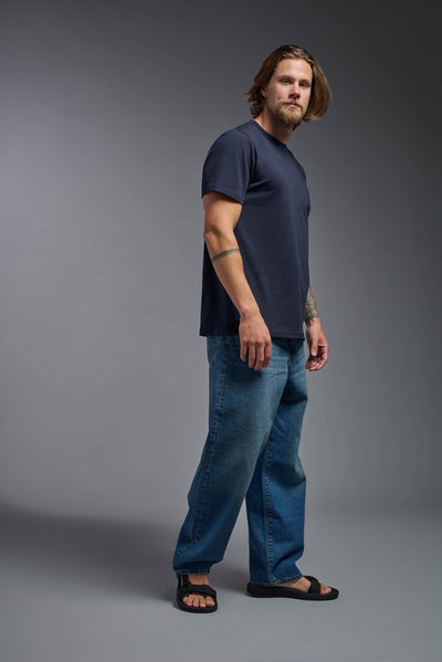 A male model wearing the unisex Organic Soft Cotton T-shirt in the color nova, made from 100% certified organic cotton, shot from a full body side view. This shirt is unisex and made in the USA. #color_nova