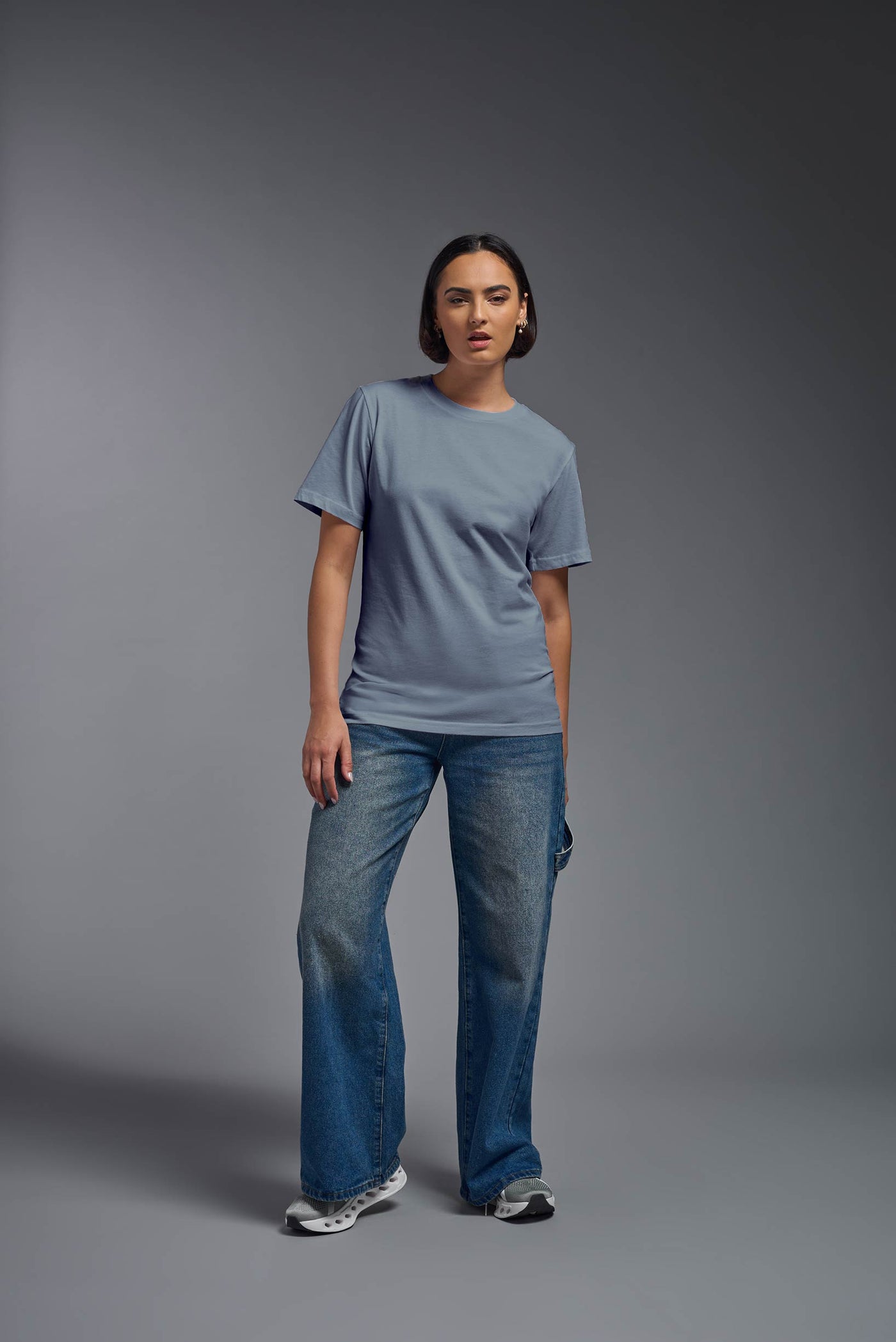 A female model wearing the unisex Organic Soft Cotton T-shirt in the color canyon blue, made from 100% certified organic cotton, shot from a full body front view. This shirt is unisex and made in the USA. #color_canyon-blue