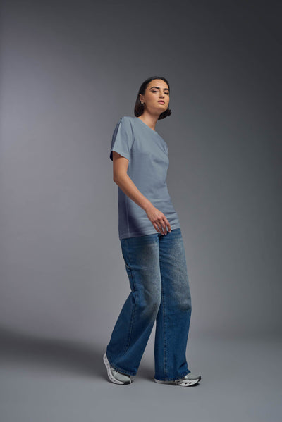 A female model wearing the unisex Organic Soft Cotton T-shirt in the color canyon blue, made from 100% certified organic cotton, shot from a full body side view. This shirt is unisex and made in the USA. #color_canyon-blue