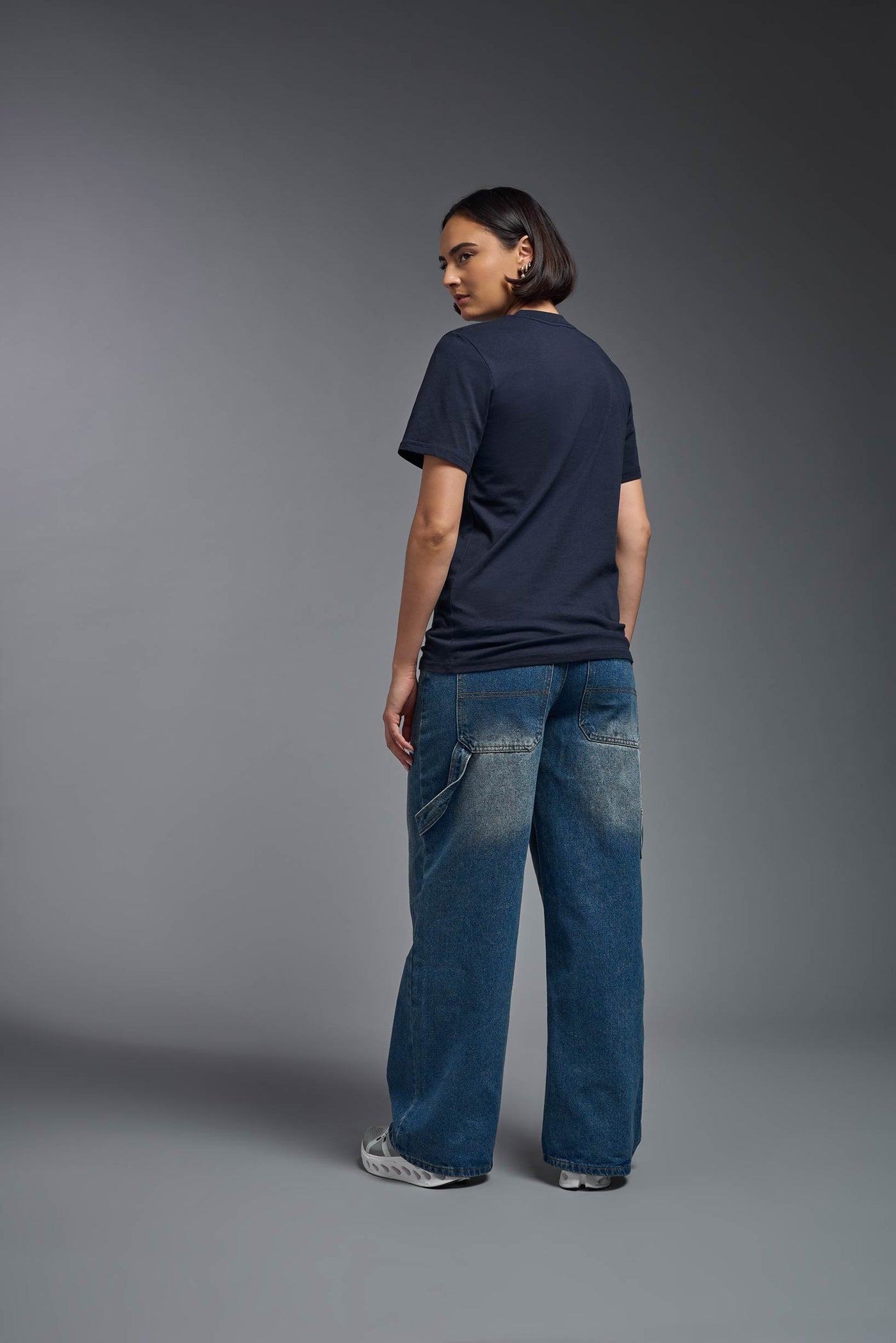 A female model wearing the unisex Organic Soft Cotton T-shirt in the color nova, made from 100% certified organic cotton, shot from a full body back view. This shirt is unisex and made in the USA. #color_nova
